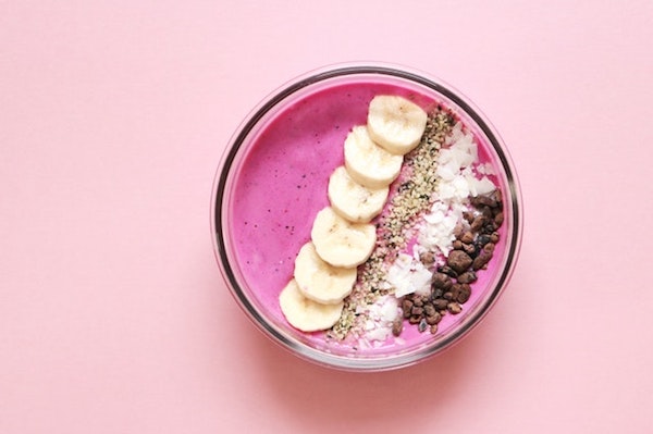 Pink acai bowl on a pink table background